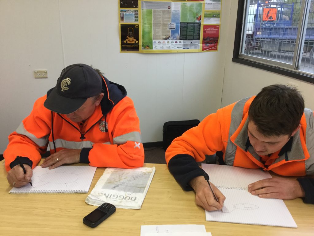 26Ten workplace grant project - Huon Valley Council.  Two people in high visibility clothing, sitting a table and writing.