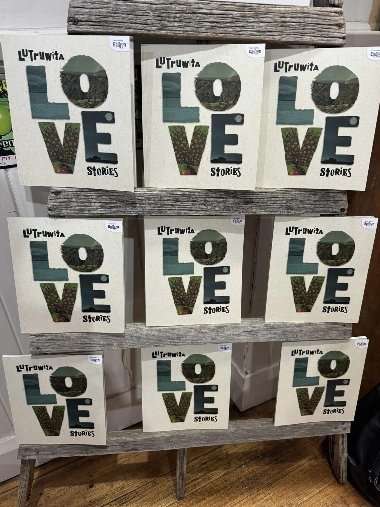 Multiple copies of Lutruwita Love Stories on a stand